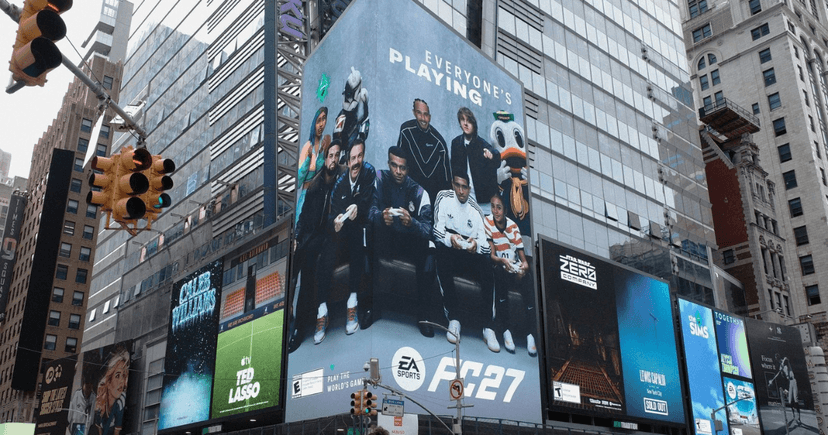Kampania EA SPORTS FC 27 na Times Square z grupą osób i postaci grających razem w piłkarską grę.